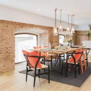 Modern dining area with brick walls and orange cushioned chairs.