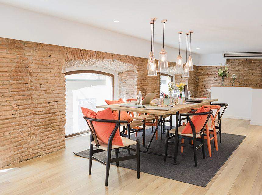 Modern dining area with brick walls and orange cushioned chairs.