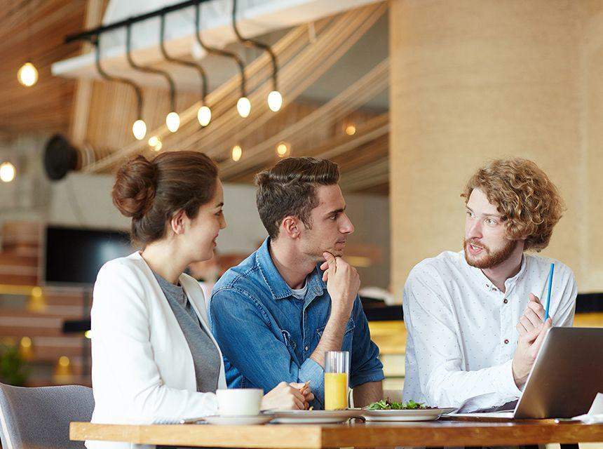 Three colleagues discussing work in a modern office setting.