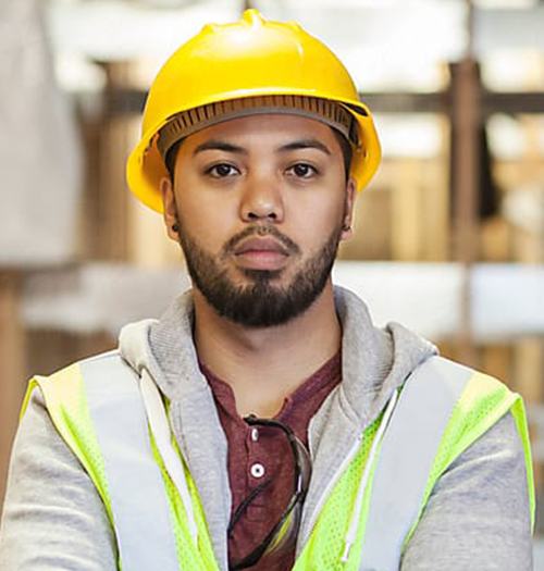 Confident construction worker wearing a yellow helmet and reflective vest.
