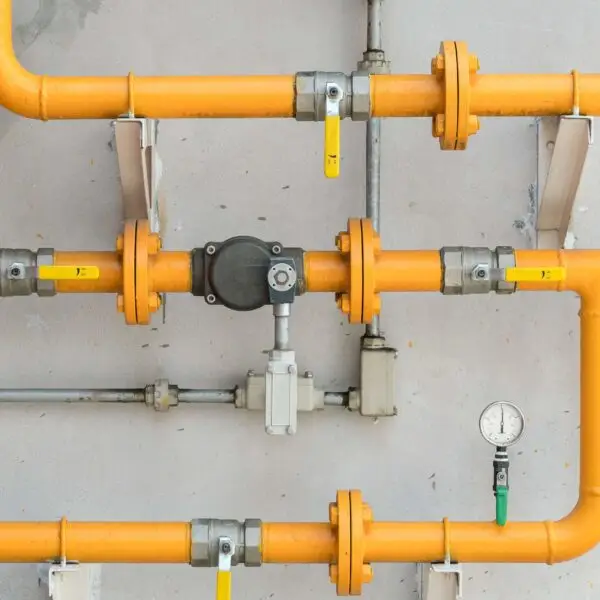 Orange industrial pipes with valves and gauge.