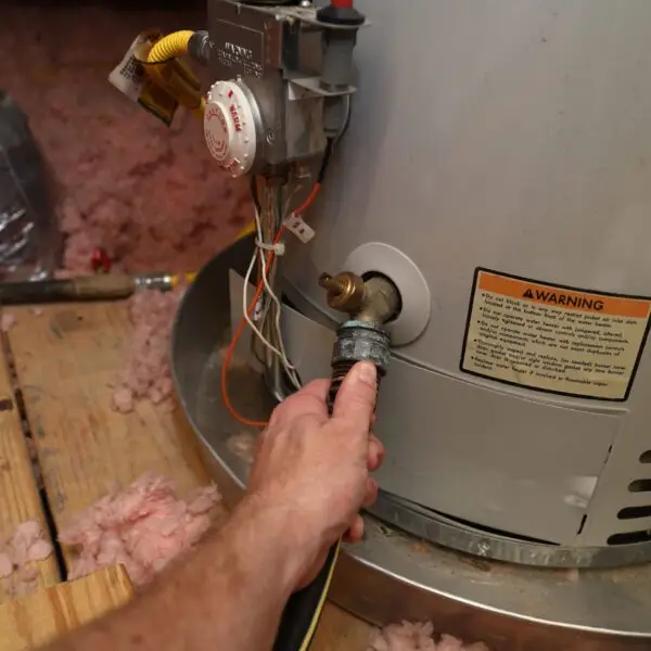Hand adjusting valve on water heater tank.